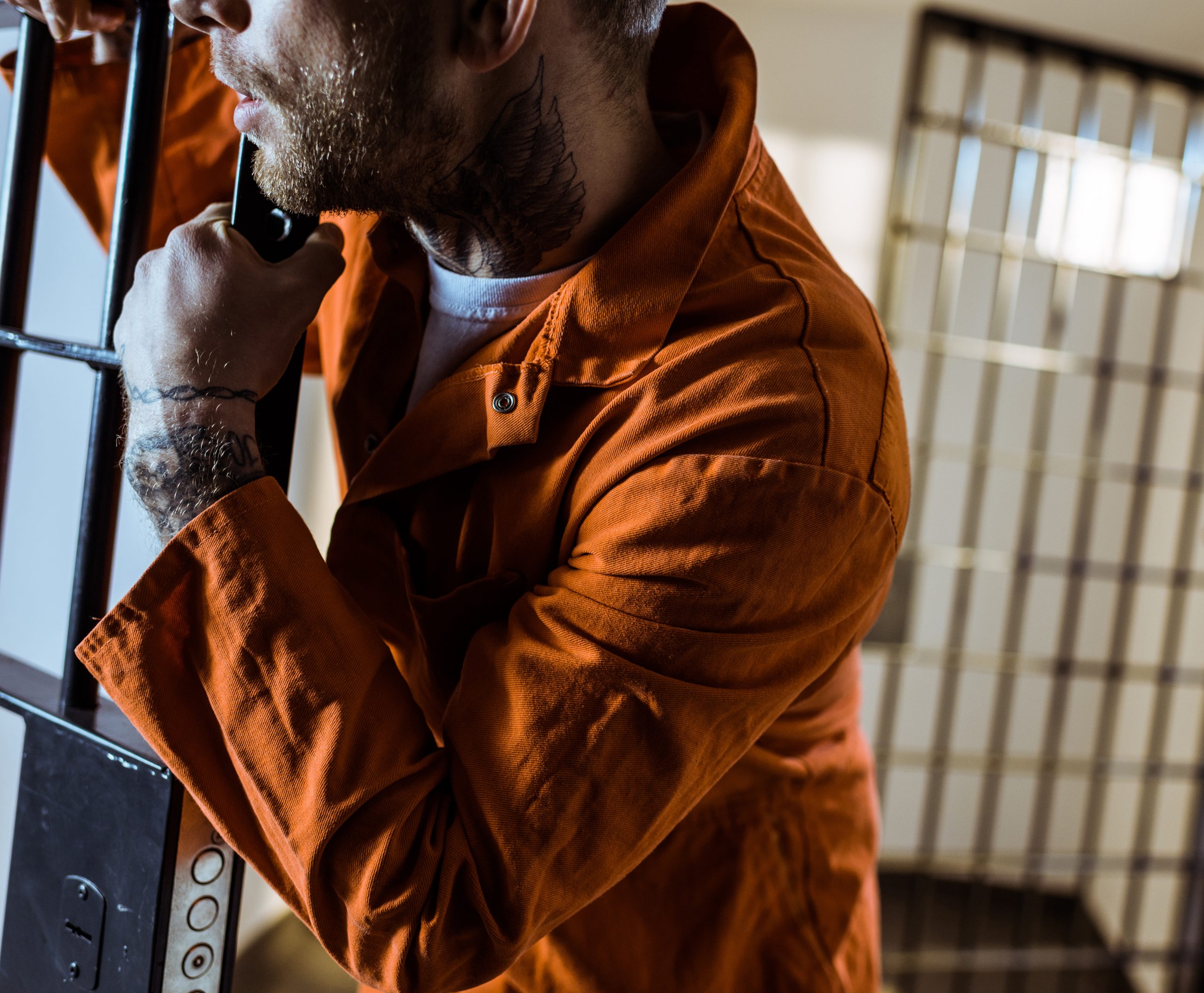 cropped image of prisoner leaning on prison bars